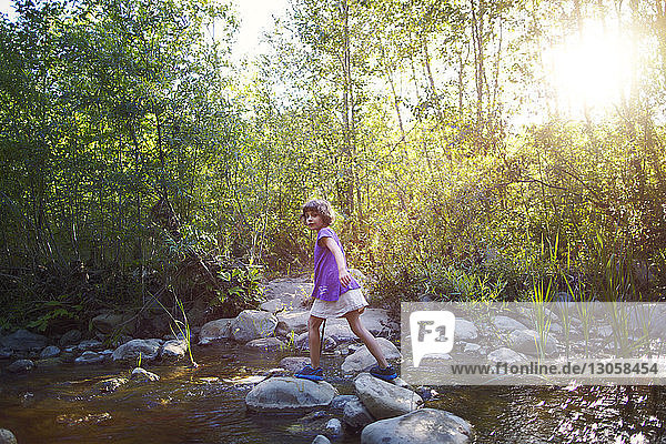 Portrait of girl walking on stepping stones in forest