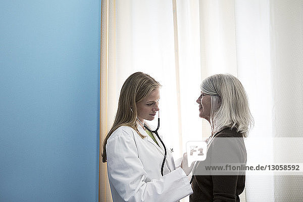 Seitenansicht des Arztes  der den Patienten im Krankenhaus mit dem Stethoskop untersucht