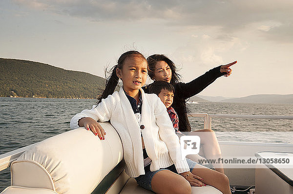 Mutter zeigt auf den See  während sie mit Kindern im Boot sitzt