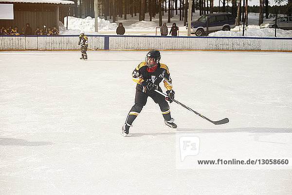 Boy playing ice hockey during sunny day