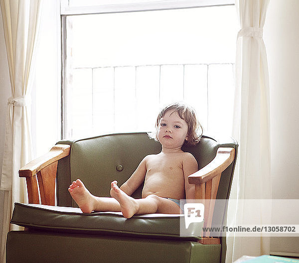 Porträt eines niedlichen Mädchens  das zu Hause auf einem Sessel sitzt