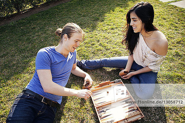 High angle view of couple playing Backgammon game at grassy field