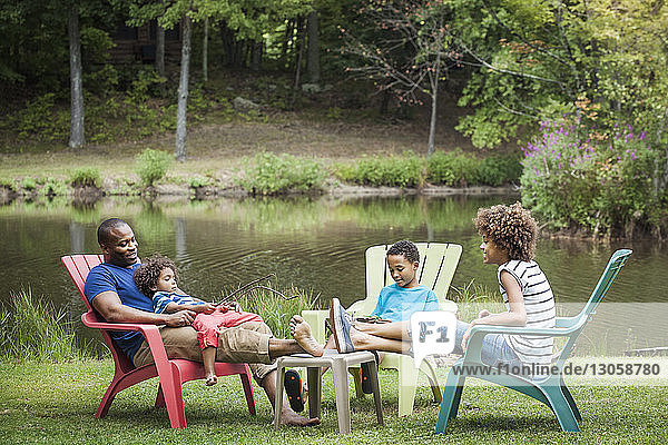 Family relaxing while sitting on chair by lake