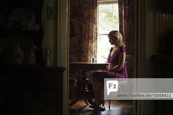 Sad woman sitting on chair by table at home