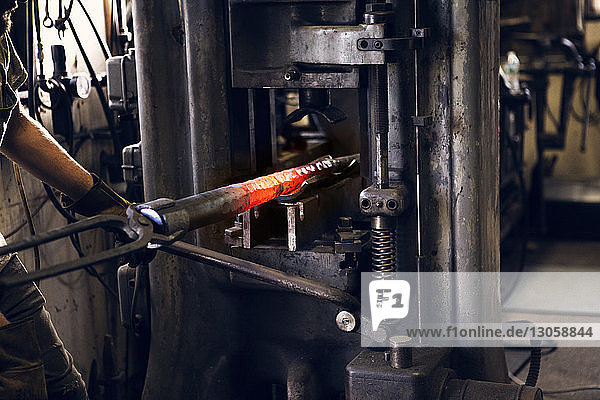 Beschnittenes Bild einer Schmiedestange in Maschinen in der Werkstatt