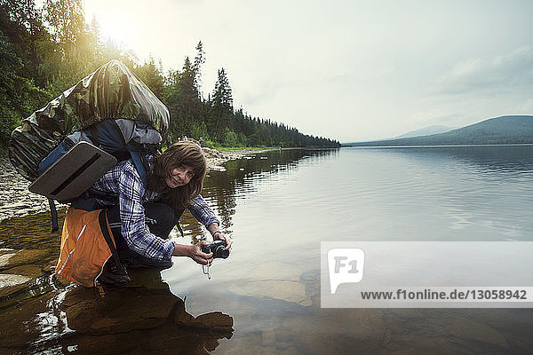 Portrait of female hiker crouching at lake