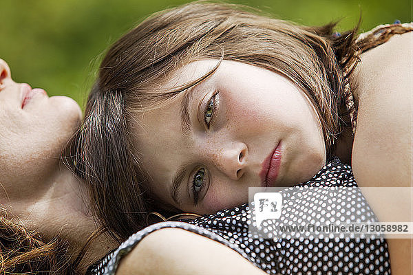 Portrait of girl lying on mother's chest at yard