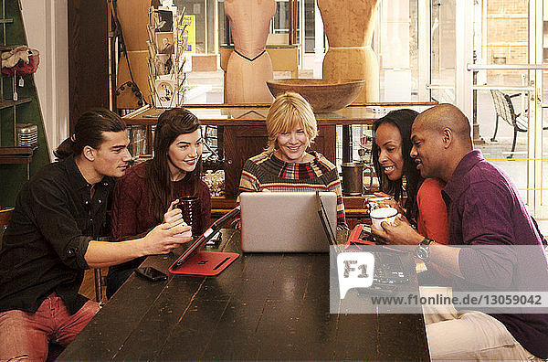 Glückliche Freunde schauen auf den Laptop  während sie im Bekleidungsgeschäft sitzen