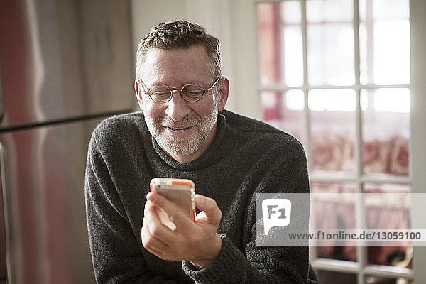Lächelnder Mann benutzt Smartphone zu Hause