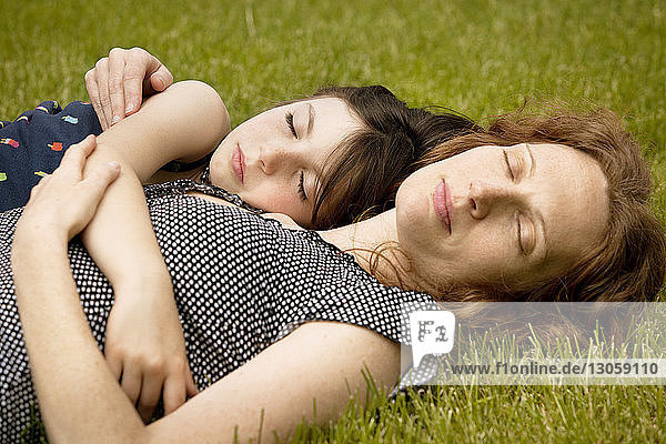 Girl sleeping with mother at backyard