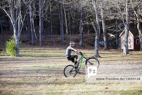 Side view of man mountain biking in forest