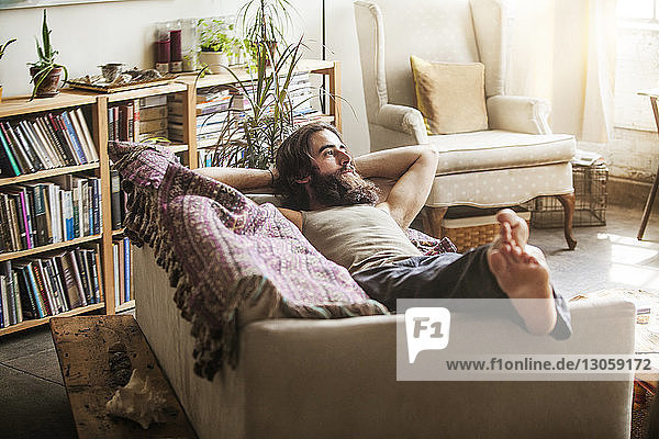 Nachdenklicher Mann entspannt sich zu Hause auf dem Sofa