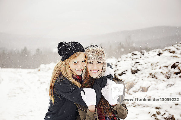 Porträt einer Frau  die einen Freund umarmt  während sie auf einem schneebedeckten Feld steht
