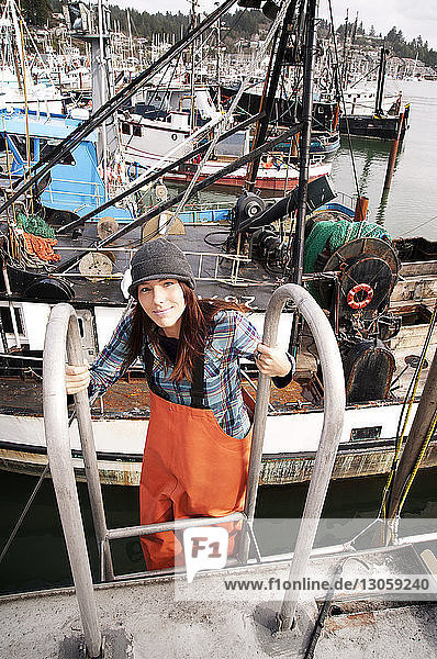 Hochwinkelaufnahme einer Frau  die auf einer Leiter am Fischerboot steht