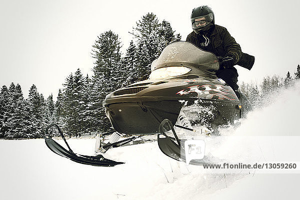 Man riding snowmobile on snow field in forest