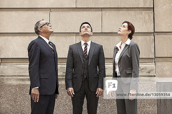 Business people looking up while standing against wall