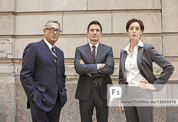 Portrait of confident business people standing against wall