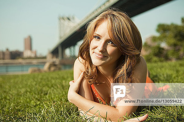 Portrait of smiling woman lying on grassy field