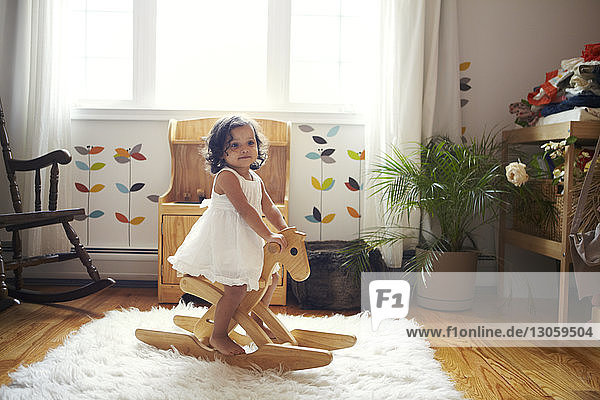 Girl playing while sitting on rocking horse at home