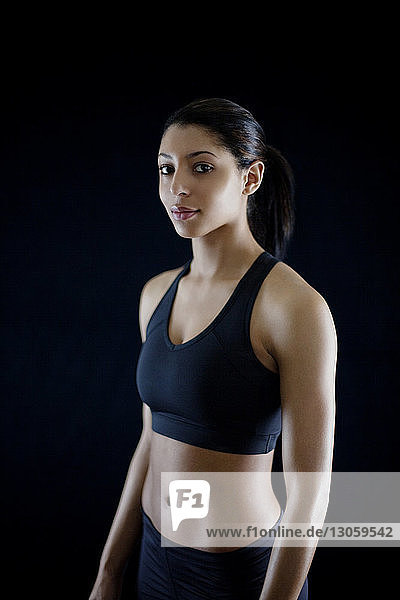 Beautiful sportswoman standing against black background
