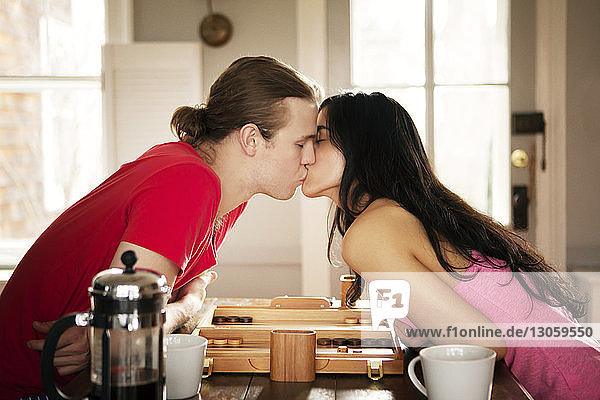 Passionate couple kissing while sitting at table