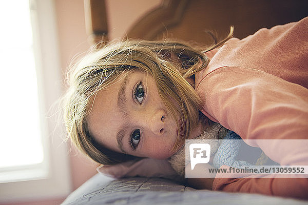 Close-up portrait of girl lying on bed at home