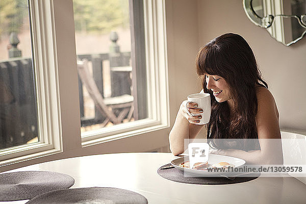 Happy woman by breakfast table at home