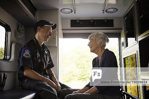 Sanitäter lachen mit Patient  während sie im Krankenwagen sitzen