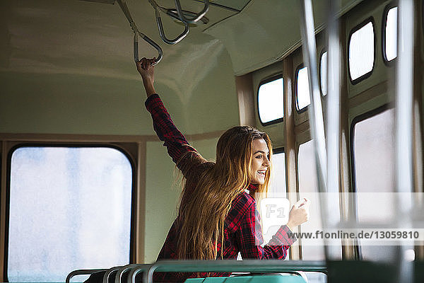 Glückliche Frau schaut durch Straßenbahnfenster