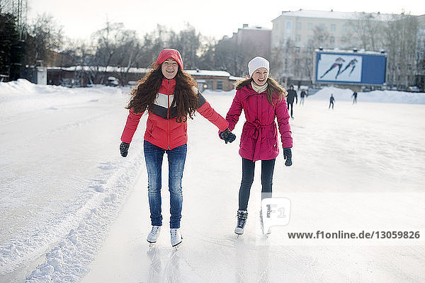 Happy friends ice-skating in park