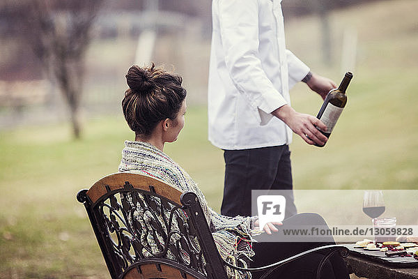 Frau sieht Mann mit Weinflasche in der Hand an