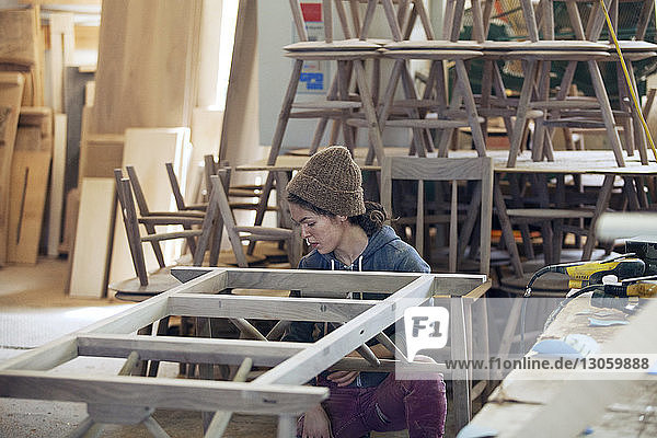 Tischlerin untersucht Holzrahmen in Werkstatt