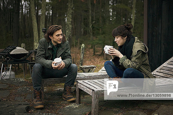 Paar mit Kaffeetassen  das auf einem Liegestuhl auf dem Campingplatz sitzt