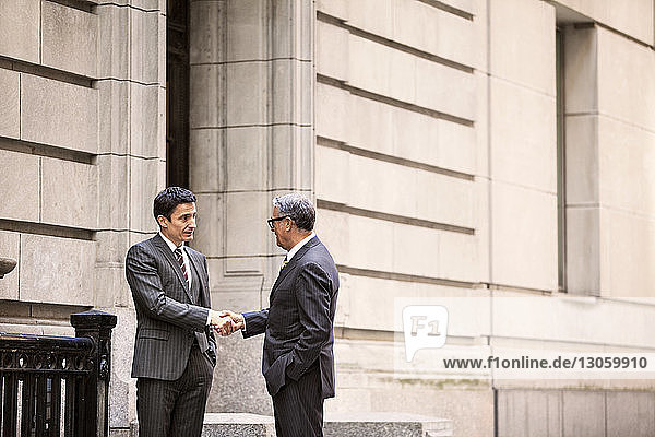 Businessmen shaking hands while standing at city street