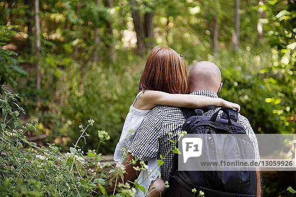 Rückansicht eines Vaters  der seine Tochter im Wald trägt