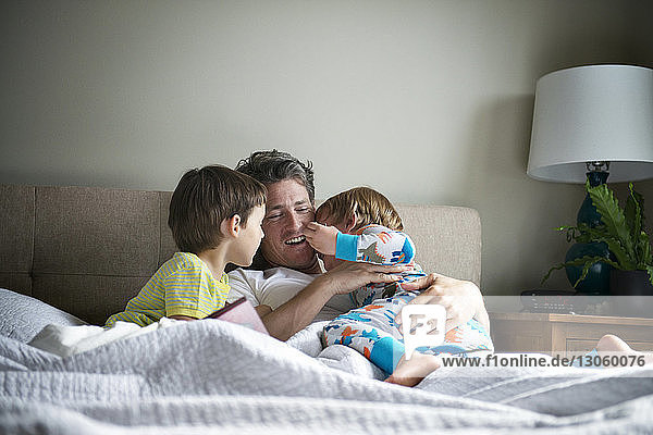 Happy father relaxing with sons on bed at home