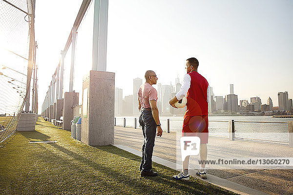 Mann hält Ball in der Hand  während er mit seinem Vater auf dem Fußballplatz am East River in der Stadt spricht