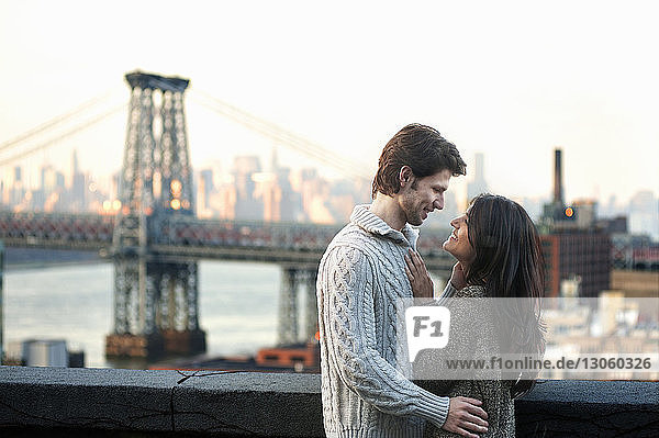 Happy young couple standing against Williamsburg Bridge