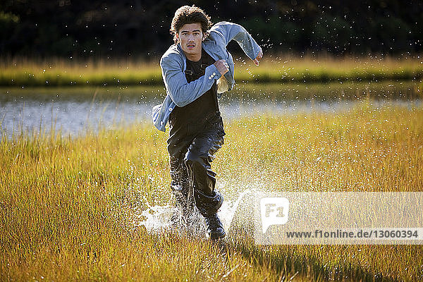 Portrait of man running on grassy field