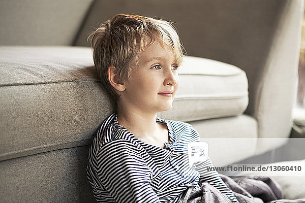 Close-up of cute boy leaning against sofa at home