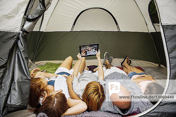 Junge nimmt Selfie  während er mit seiner Familie im Zelt liegt