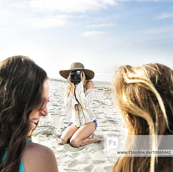 Frau fotografiert Freunde am Strand