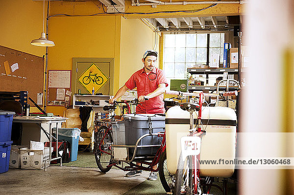 Mann mit Container auf Fahrrad in Werkstatt