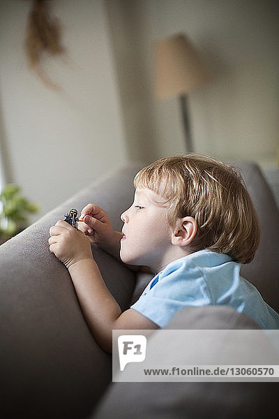 Junge spielt zu Hause auf dem Sofa mit Spielzeug