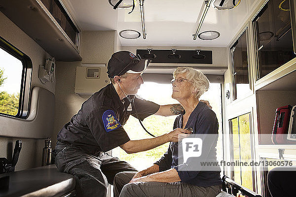 Sanitäter untersuchen Patient mit Stethoskop  während sie im Krankenwagen sitzen