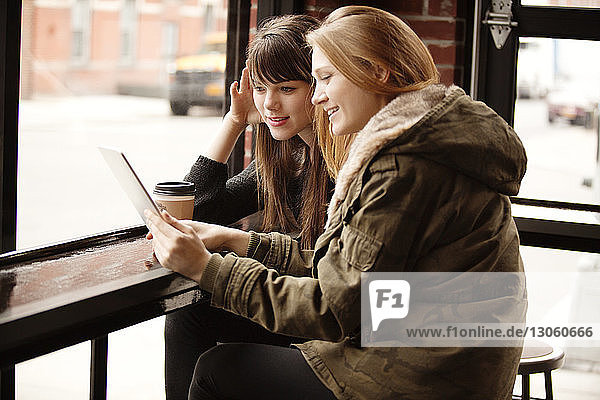 Freundinnen benutzen digitales Tablett im Café