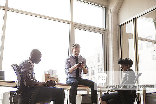 Business people using communication device while sitting at office