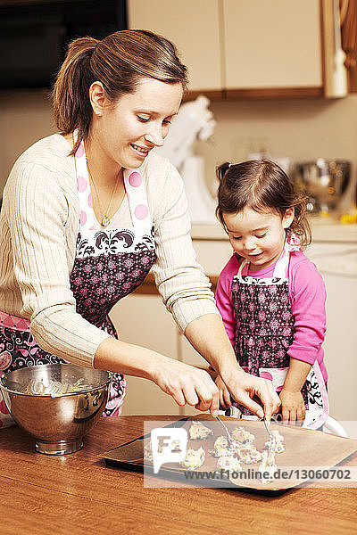 Mother and daughter preparing food on table in kitchen