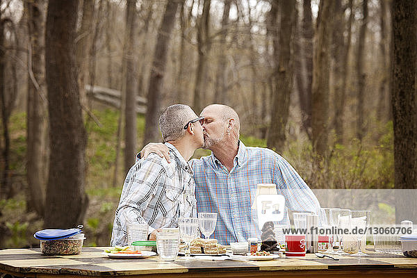 Schwules Paar küsst sich am Frühstückstisch