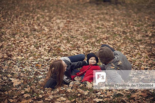 Parents with baby relaxing on field in park